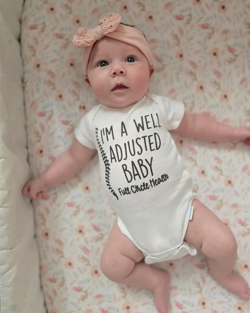 A baby in a Full Circle Health "I'm a well adjusted baby" onesie